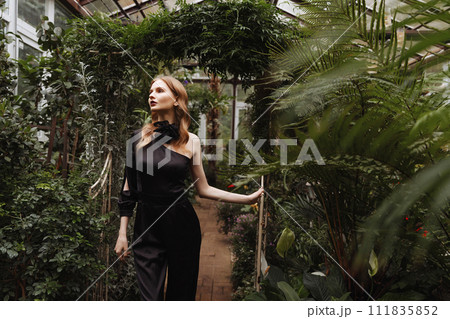 A woman walking through a greenhouse. A woman walking through a greenhouse. 111835852
