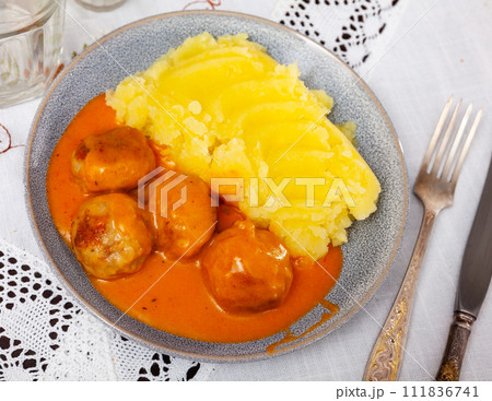 white round plate with meatballs sprinkled with chopped dill in tomato sauce with mashed potatoes 111836741