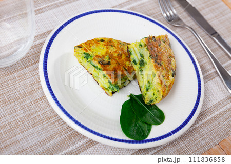 Few small pieces of fluffy egg and spinach omelet are on plate decorated with edible green Few small pieces of fluffy egg and spinach omelet are on plate decorated with edible green 111836858