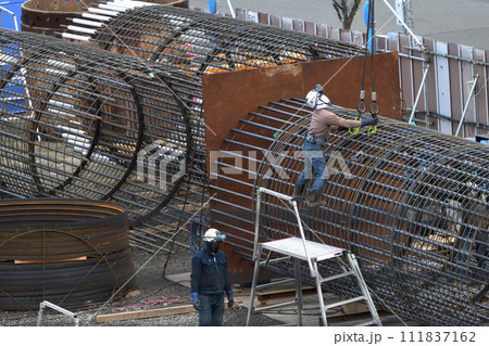 新築マンション　杭基礎工事の鉄筋カゴを移動する鉄筋工の作業風景 111837162