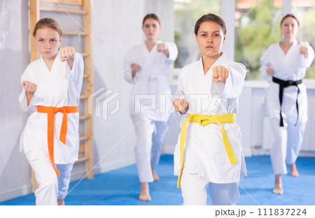 Adolescent karateka practicing punches during kata at group training Adolescent karateka practicing punches during kata at group training 111837224
