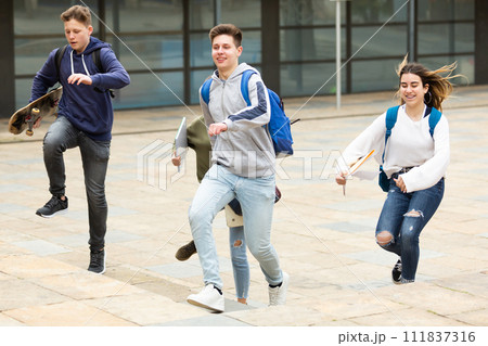 Group of cheerful students running along city street Group of cheerful students running along city street 111837316