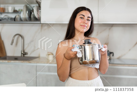 Young woman posing with saucepan in kitchen at home Young woman posing with saucepan in kitchen at home 111837358
