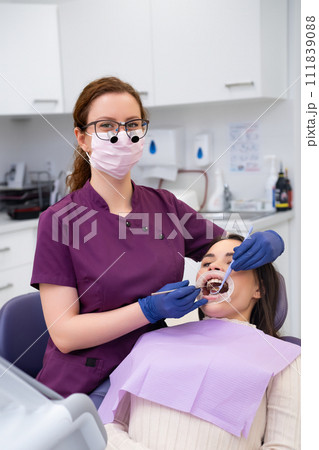 Portrait of young female doctor performs teeth treatment to patient. Portrait of young female doctor performs teeth treatment to patient. 111839088