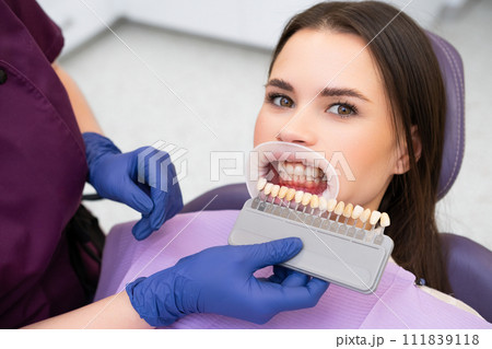 Woman patient and shades of the implants for teeth whitening in doctors hands. 111839118