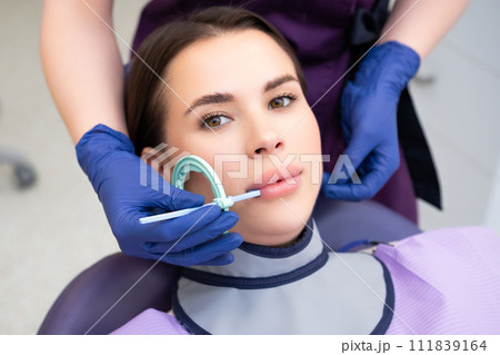 Process of preparation of patient before dental X-ray procedure. Woman instructs patient on how to tilt head before dental X-ray procedure 111839164