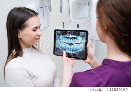 Dental Professional Demonstrating Jaw and Teeth X-ray Scan to Client at Dental Practice.  111839199