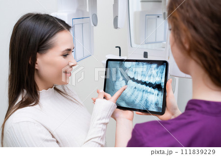 Dentist showing to patient jaw teeth x ray image at dental office. 111839229