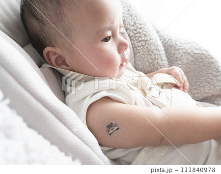 右腕に注射跡の絆創膏を貼っている生後半年のハーフの男の子赤ちゃん 111840978