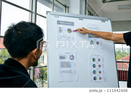 Close up of professionals engaged in a business meeting with one person presenting a report with graphs and charts 111842806