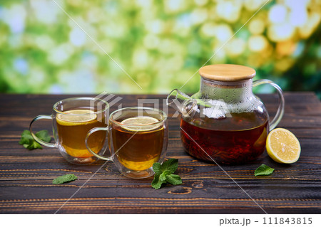 natural organic herbal tea in glass teapot and cup on a wooden table natural organic herbal tea in glass teapot and cup on a wooden table 111843815