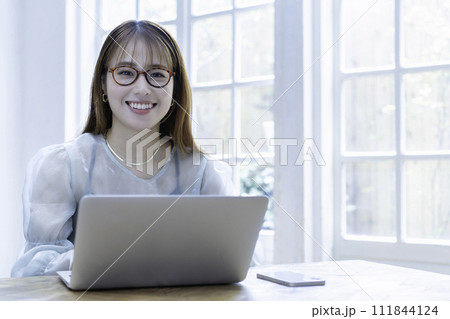 日差しが差し込む明るい部屋でノートパソコンを使う若い女性 日差しが差し込む明るい部屋でノートパソコンを使う若い女性 111844124