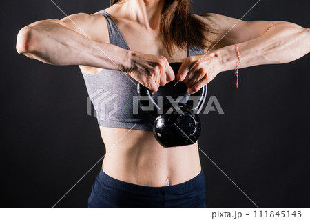 Woman in sportswear doing crossfit workout with kettle bell on dark yellow red background. Woman in sportswear doing crossfit workout with kettle bell on dark yellow red background. 111845143