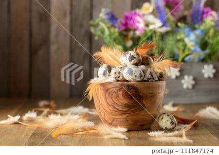 Easter composition with quail eggs, feathers, and spring flowers on a old wooden table. 111847174