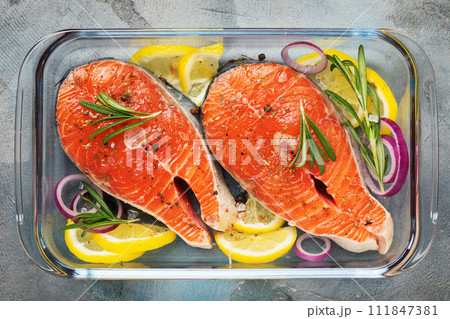 Red fish steaks with various ingredients in a glass baking dish on the table, top view of fresh trout 111847381