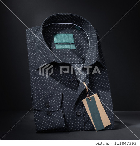 Black folded long sleeve men's shirt on a dark background, close-up Black folded long sleeve men's shirt on a dark background, close-up 111847393