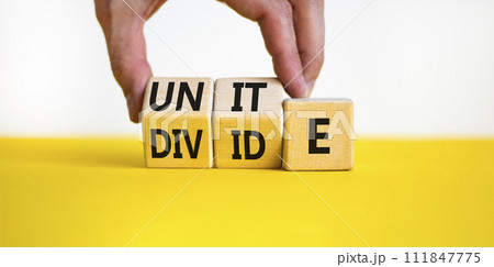 Unite or divide symbol. Concept word Unite or Divide on wooden cubes. Beautiful yellow table white background. Businessman hand. Business unite or divide concept. Copy space. 111847775