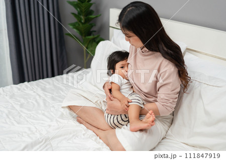 mother feeding breast her toddler baby on bed 111847919