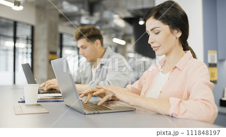 IT specialists typing on laptops, working in office together, modern technology IT specialists typing on laptops, working in office together, modern technology 111848197