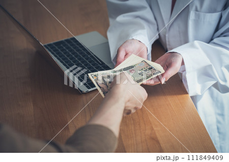 医師にお金を渡す患者 111849409
