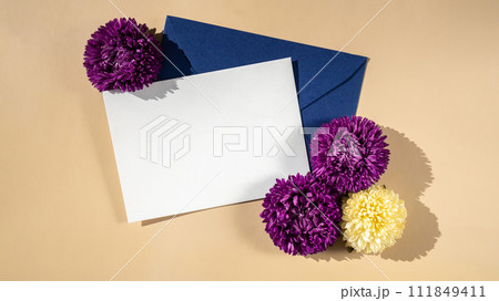 Composition with empty paper note and envelope beautiful spring violet and white flowers on beige background. Mockup card invitation greeting card postcard copy space template Composition with empty paper note and envelope beautiful spring violet and white flowers on beige background. Mockup card invitation greeting card postcard copy space template 111849411