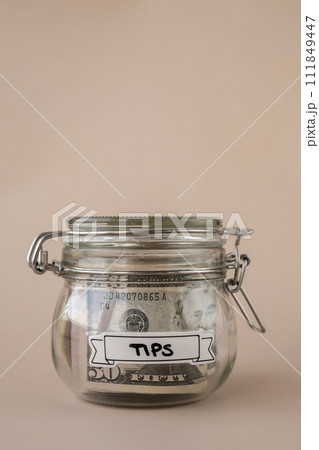 Glass jar full of American currency dollars cash banknote with text TIPS. Preparation saving money. Moderate consumption and economy 111849447