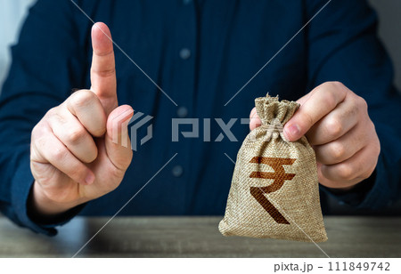 A man warns with his finger offering a indian rupee money bag. Funding and grants. Banks and finance. Bad credit history. Strict conditions. Loan for a specific purpose. Terms of borrowing money. 111849742