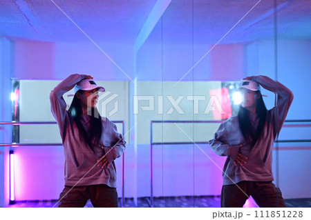 Young woman dancing hip hop style in front of mirror at studio with neon light 111851228