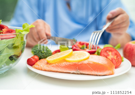 Asian elderly woman patient eating salmon steak breakfast with vegetable healthy food in hospital. 111852254