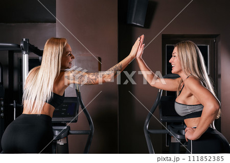 Two attractive sporty women riding exercise bikes during cycling training in gym 111852385