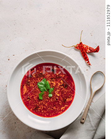 Traditional red soup borscht made with beetroot. National Russian and Ukrainian soup, kitchen, food. Tasty beetroot soup with greens in bowl on neutral pastel background. Top view, flat lay Traditional red soup borscht made with beetroot. National Russian and Ukrainian soup, kitchen, food. Tasty beetroot soup with greens in bowl on neutral pastel background. Top view, flat lay 111852979