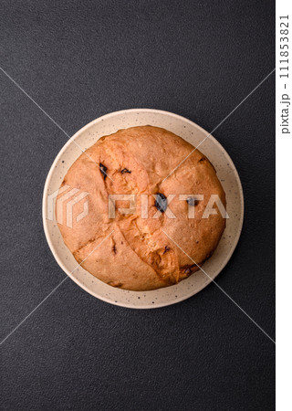 Delicious sweet holiday panettone cake with zest and raisins on a ceramic plate 111853821
