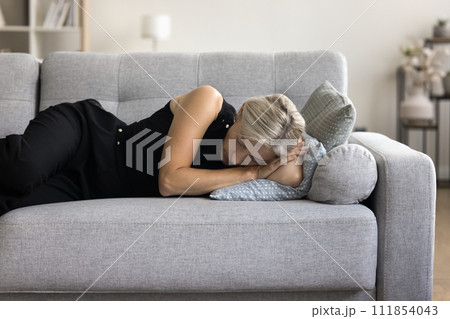 Woman lying on sofa take daytime nap in living room 111854043