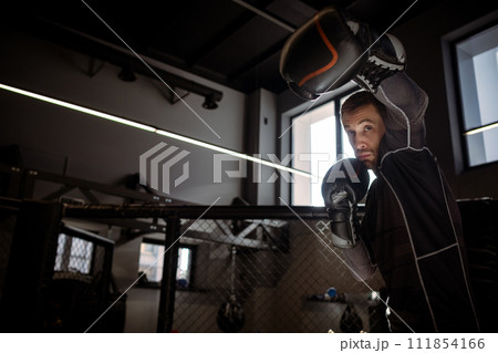 Boxer throwing powerful left hook during shadowboxing in gym Boxer throwing powerful left hook during shadowboxing in gym 111854166