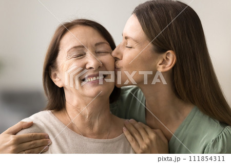 Happy loving adult daughter woman hugging and kissing senior mom 111854311