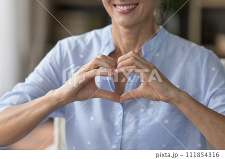 Smiling mature woman showing symbol of love, cropped shot 111854316