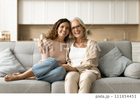 Cheerful senior mother and daughter woman sitting on home couch 111854451