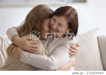 Happy cheerful older retired mom hugging joyful adult child 111854459