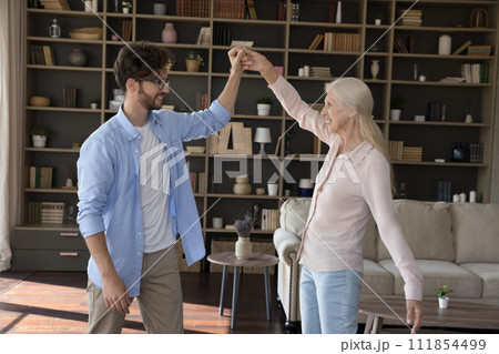 Vivacious older woman and grownup son dancing at home 111854499