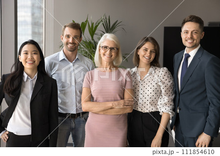 Mature business leader and multiethnic younger employees smiling at camera Mature business leader and multiethnic younger employees smiling at camera 111854610
