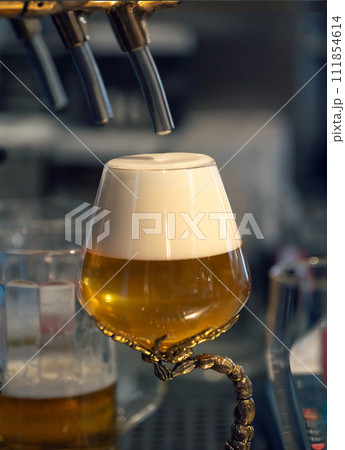 Full glass of fresh light beer near beer tap in pub. Perfect for beer enthusiasts and bar owners. Beer craft and Octoberfest concept. Vertical. 111854614