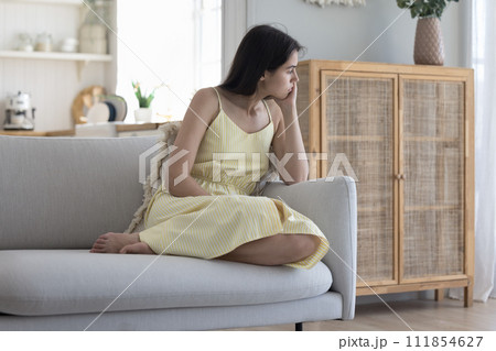 Sad pensive woman sits on sofa thinking about relationships 111854627