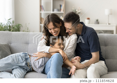 Happy young parents cuddling sweet adorable kid girl on couch 111854628