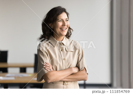 Positive mature professional woman posing in office with hands folded Positive mature professional woman posing in office with hands folded 111854769