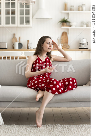 Vertical shot pensive young woman sit on sofa with smartphone 111854808