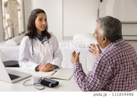 Serious young Latin doctor woman meeting with senior Indian patient 111854998