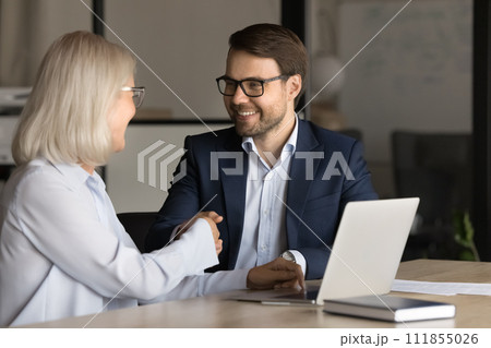 Positive successful professional shaking hands with senior colleague woman 111855026