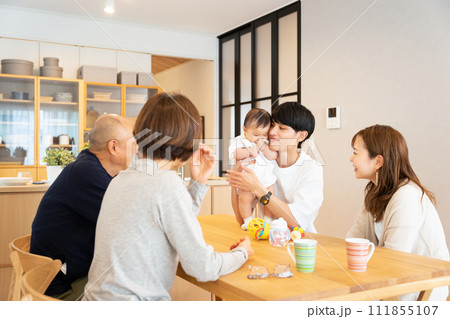 リビングで赤ちゃんを抱っこする父親と母親と祖父母の3世帯の5人家族 111855107