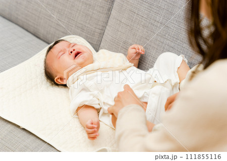 ソファで0歳の赤ちゃんのオムツ替えをする母親 ソファで0歳の赤ちゃんのオムツ替えをする母親 111855116
