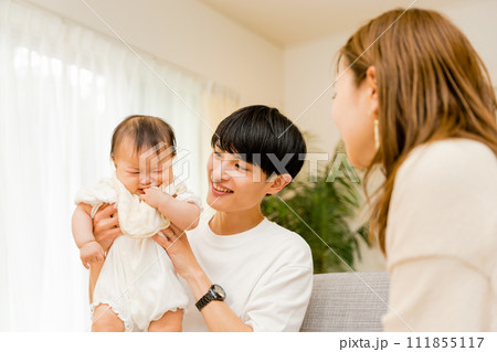 泣いている0歳の赤ちゃんを抱っこする30代の日本人男性のお父さんと見守るお母さんの3人家族ファミリー 泣いている0歳の赤ちゃんを抱っこする30代の日本人男性のお父さんと見守るお母さんの3人家族ファミリー 111855117